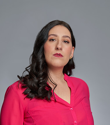 Donna con camicia rosa su sfondo grigio.