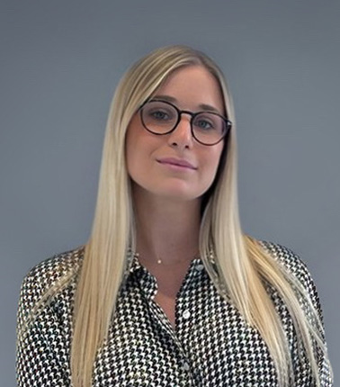 Donna bionda con occhiali e camicia pied de poule.