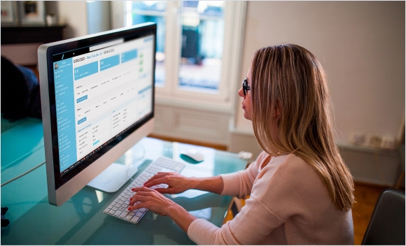 Donna che lavora al computer in un ambiente casalingo.