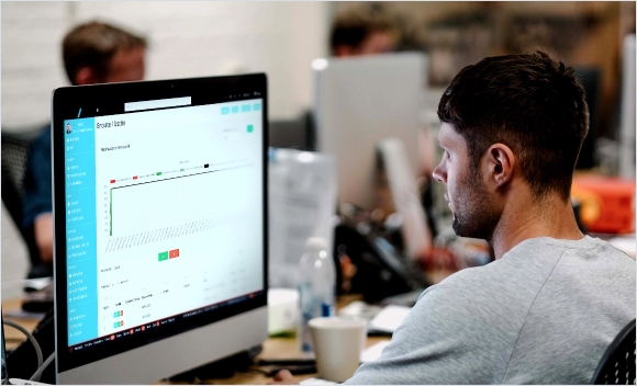 Uomo che osserva un grafico a schermo in ufficio.